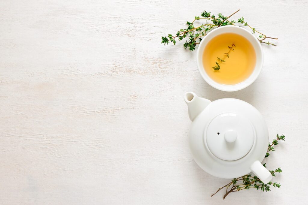 Théière avec tasse de thé sur fond blanc et pur